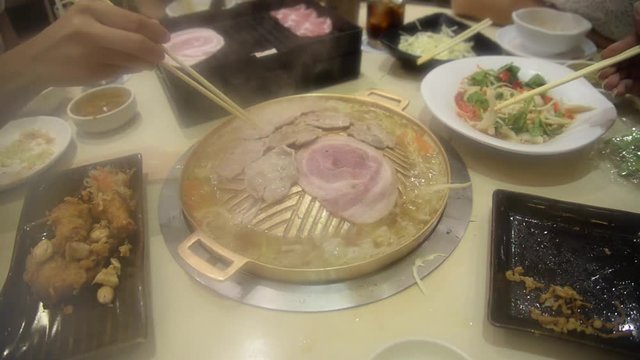 Korean grilled style on hot gold stove served with vegetables like needle-mushroom, pork and beef slices and bacon eating