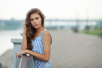 Closeup portrait of beautiful woman in summer dress posing in city river park pier enjoying weekend. Playful and beautiful caucasian girl on warm sunny day