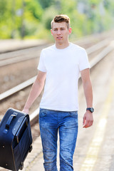 The young man at the railway station. - obrazy, fototapety, plakaty