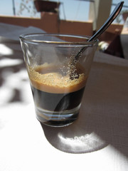 Closeup of espresso coffee in a glass cup with blurred background