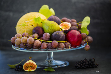 Beautiful still life with grapes and figs and other fruits on stone background.
