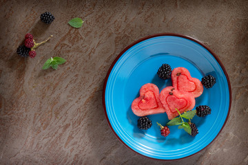 Slice of watermelon heart and berry fruit on brown stone backgro