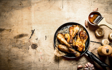 Fried chicken legs in pan with tomato sauce
