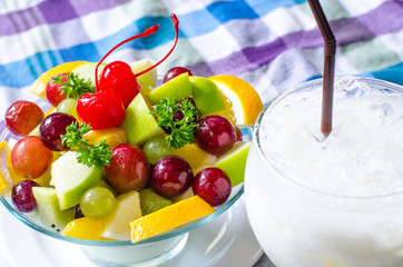 Bowl of healthy fresh fruit salad and milk on pattern of Thai hand made fabric background