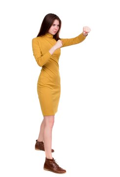skinny woman funny fights waving his arms and legs. Long-haired brunette in a mustard-colored dress in boxing.