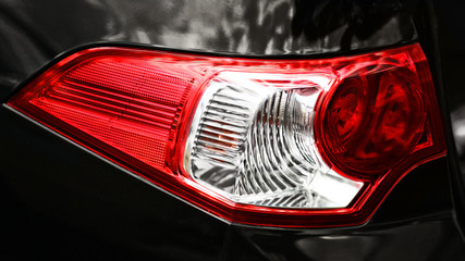 Closeup of a taillight on a modern black car with reflection.