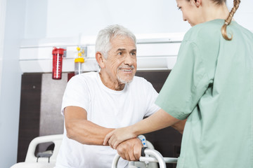 Fototapeta premium Nurse Helping Smiling Senior Man In Using Walker