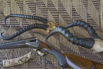 Foto auf Acrylglas Antireflex Hunting in Africa. Hunting gun, lance, knife, trophy on a african mat © stsvirkun