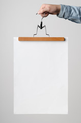 A3 Poster Mock-Up - Man holding a poster on a clothes hanger on a white background.
