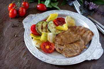 Grilled steak meat pork and grilled vegetables on brown stone ba