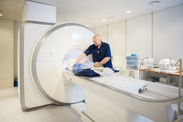Male Radiologist Preparing Woman For MRI Scan