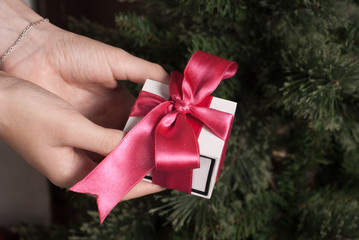 Gift with pink ribbon, white box in female hands, Christmas surprise,
