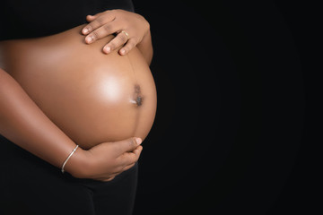 African woman with hands on her pregnant tummy