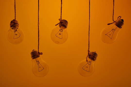 five incandescent light bulbs hanging on a yellow background