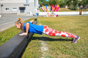 beautiful caucasian woman doing push-ups on bench outdoors, fitness and sport lifestyle