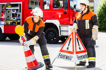 Feuerwehrfrauen stellen beim Notfalleinsatz ein Warnschild auf