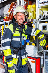 Naklejka premium Feuerwehrmann in Uniform lehnt am Einsatzfahrzeug der Feuerwehr