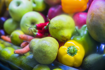 a lot of fruit: apples, pears, oranges, peppers, pineapple on store shelves closeup