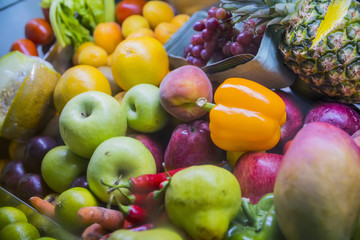 a lot of fruit: apples, pears, oranges, peppers, pineapple on store shelves closeup