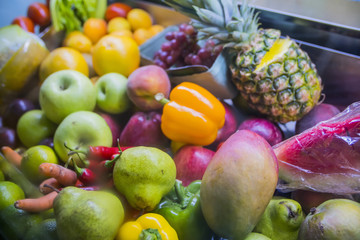 a lot of fruit: apples, pears, oranges, peppers, pineapple on store shelves closeup