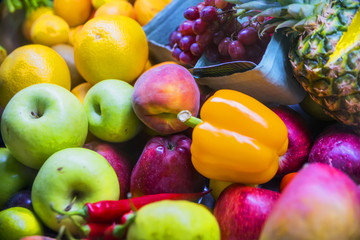 a lot of fruit: apples, pears, oranges, peppers, pineapple on store shelves closeup