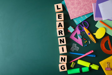 Colourful stationery and word LEARNING on chalkboard