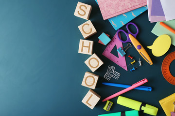 Colourful stationery and word SCHOOL on chalkboard