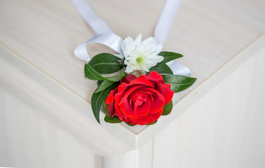 Red boutonniere lie on the wooden table