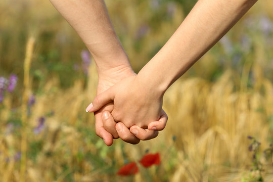 Young couple holding hands on beautiful field