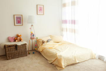 Fototapeta na wymiar Bed in light children room interior