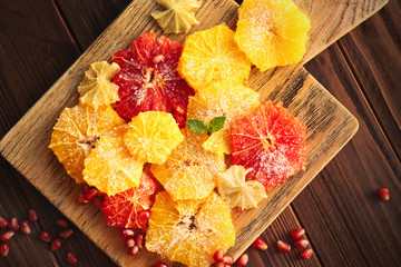 Different citrus slices covered with sugar on cutting board, closeup
