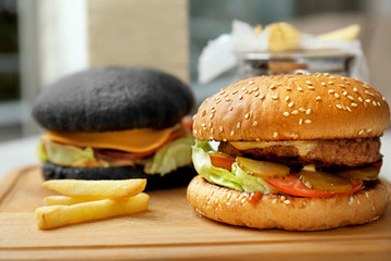Two different burgers on wooden cutting board
