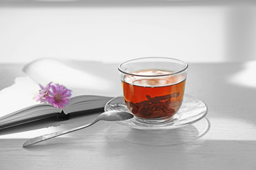 Cup of tea with notebook and spoon on table