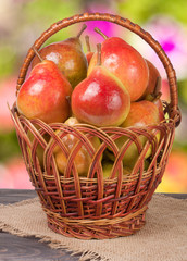 pears in a wicker basket on wooden table with blurred background