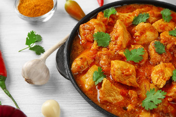 Chicken curry with vegetables on wooden background