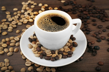 Cup of coffee with beans on wooden background