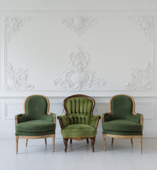 Set of green wooden vintage chairs standing in front a white wall design bas-relief stucco...