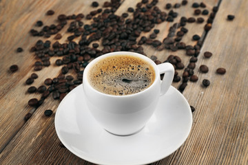 Cup of coffee with beans on wooden background