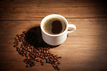 Cup of coffee with beans on wooden background