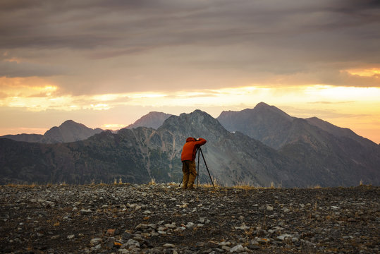 Rear view of man taking picture of mountains against cloudy sky