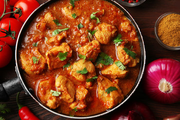 Tasty chicken curry in pan and spices, closeup