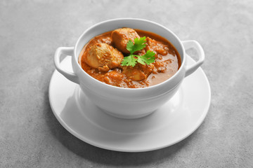 Tasty chicken curry in soup plate on grey background