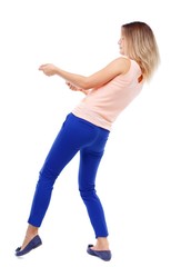 back view of standing girl pulling a rope from the top or cling to something. Isolated over white background. The blonde in a pink shirt pulling rope side.