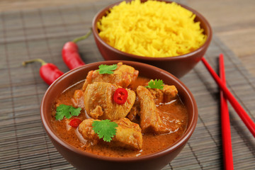 Tasty dinner with chicken curry in bowl on bamboo mat