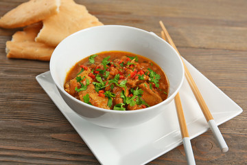 Tasty chicken curry in soup plate and chopsticks on table
