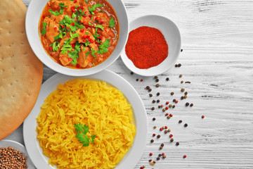 Tasty dinner with chicken curry and rice in plates on wooden background
