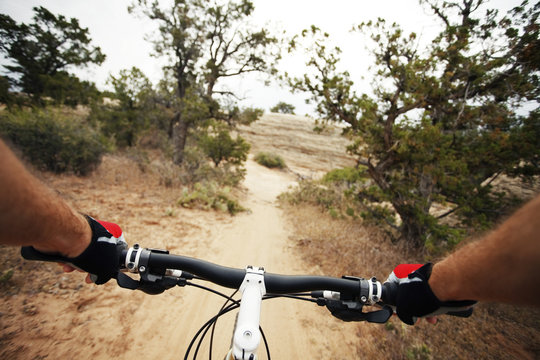 Cropped image of man riding bicycle on dirt road