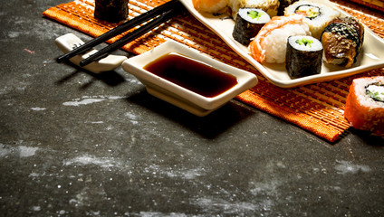 The rolls and sushi with soy sauce on bamboo stand.