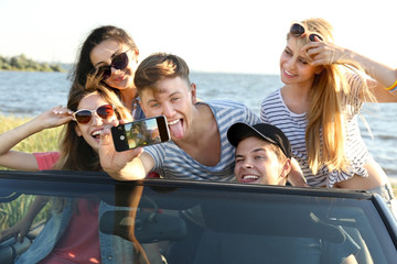 Happy friends taking selfie in car