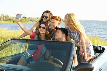 Happy friends taking selfie in car